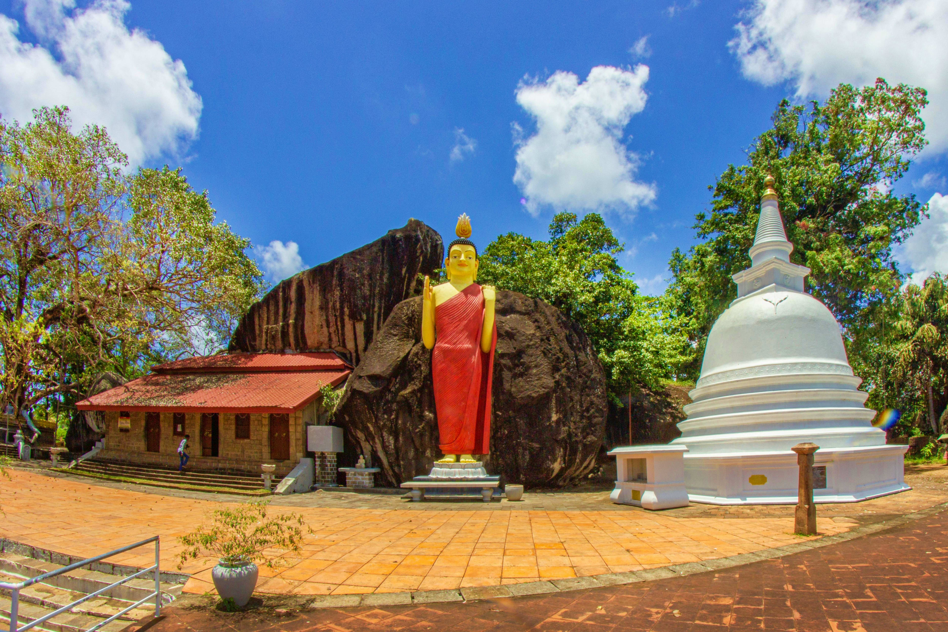 Sri Lanka Buddhist temple complex in Sri Lanka with golden Buddha statue, white stupa, red-roofed shrine building, and massive rock for
